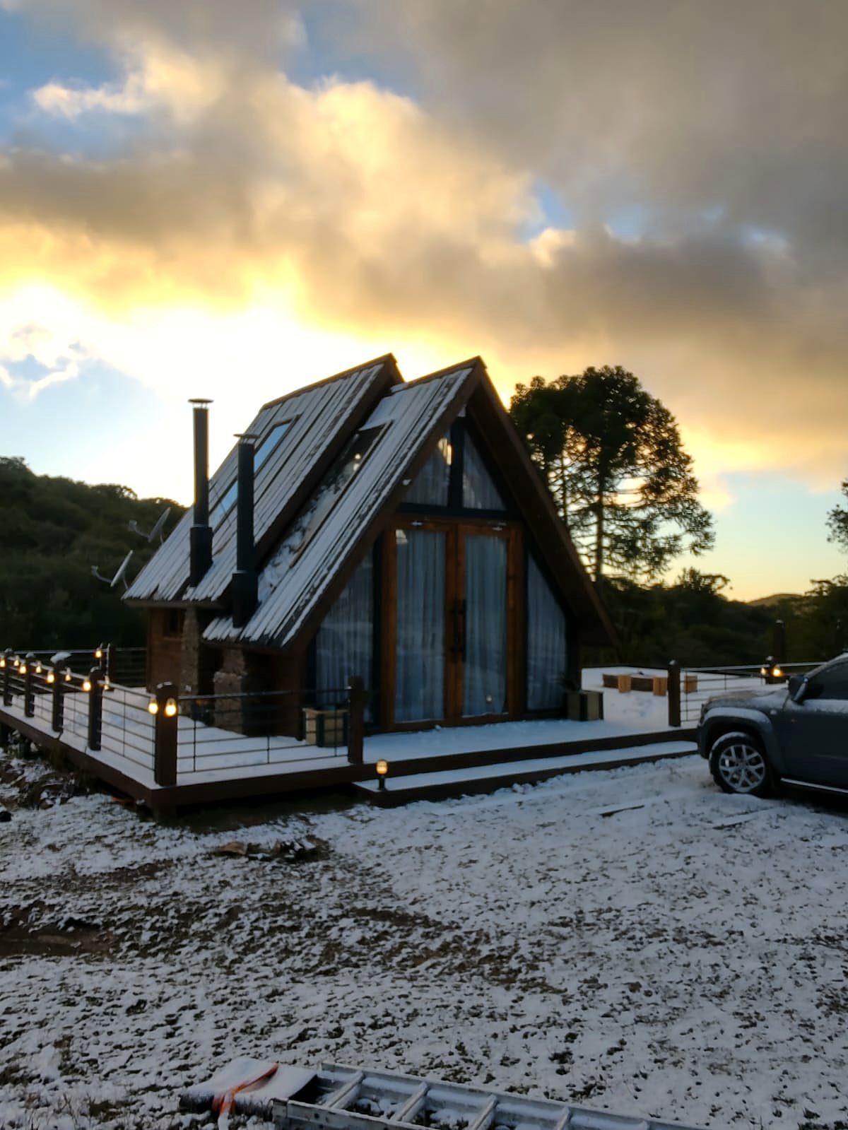 Chalé e deck cobertos de neve sob céu dourado